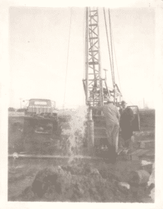 Old photo of a Prairie State Water local water well driller with construction machinery on a dirt field.