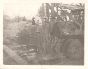 Photograph from the 1950s of the Liberg brothers, John and Patrick, standing near construction equipment at an active site.