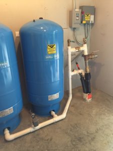 Two water well tanks connected to pipes inside of a building and installed by local water well drillers