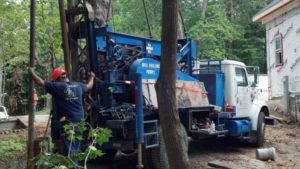 Prairie State Water service truck at a residential location with well drilling equipment