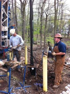 Prairie State Water workers with equipment in a forested outdoor area.