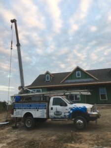 A Prairie State Water truck parked outdoors next to a well drill in front of a home in Illinois