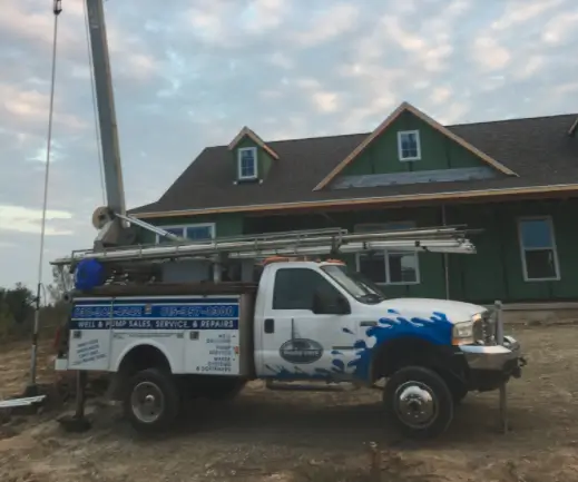 A Prairie State Water truck parked outdoors next to a well drill in front of a home in Illinois